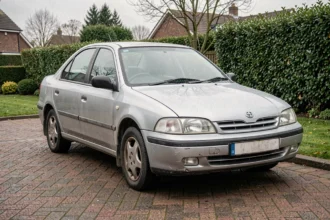 Berline essence fiable garée dans une allée résidentielle après dix ans d'utilisation, montrant une carrosserie soignée et bien entretenue