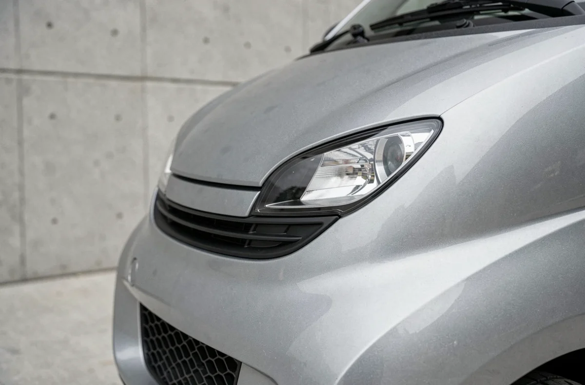 Gros plan sur la face avant d'une voiture sans permis au design premium, phares compacts et capot sculpté