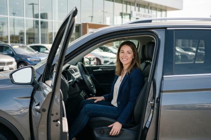 Femme souriante dans une voiture neuve en concession