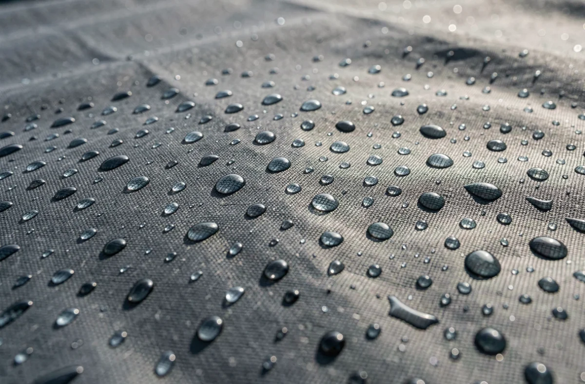 Gros plan sur un tissu de housse de voiture avec des gouttes de pluie