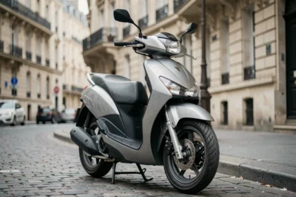 Honda Forza 125 garé sur un trottoir parisien, vue avant trois-quarts, reflets urbains sur la carrosserie argentée