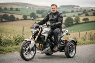 Homme en blouson moto assis sur un trois-roues motorisé sur une route de campagne, illustrant le permis moto trois roues